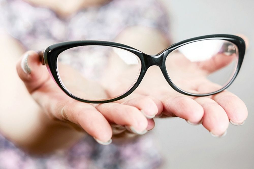 woman holding a pair of eyeglasses at the palm of her hands