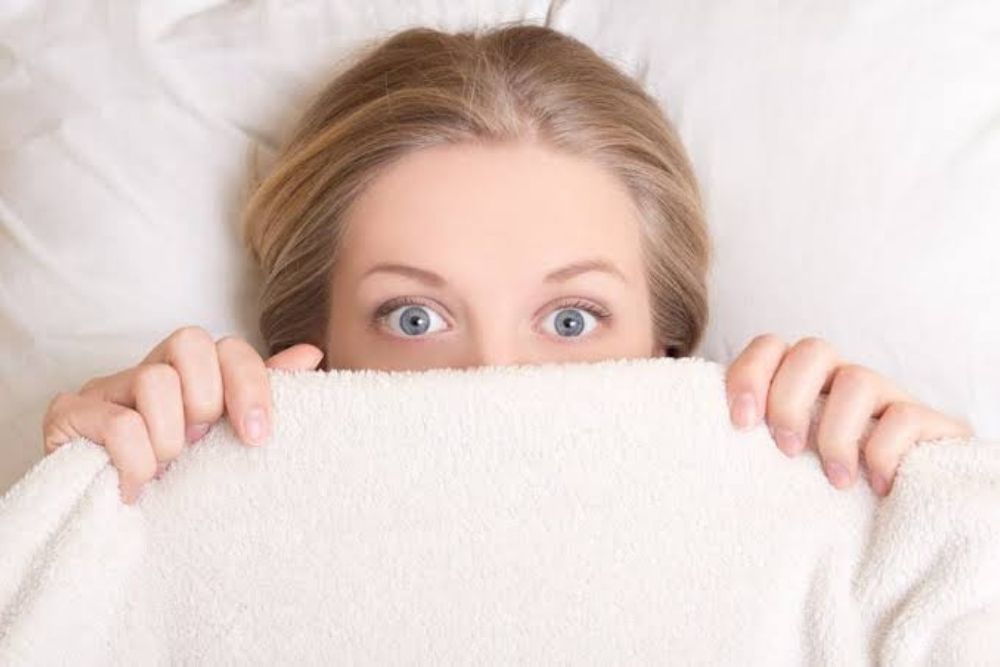 woman covering face with pillow